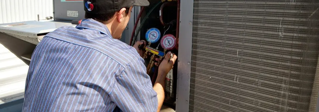 HVAC technician servicing a condenser unit in Bonham